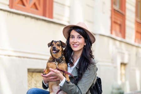 young attractive woman playing with her dog on the city street, lifestyle people concept. Beauty...