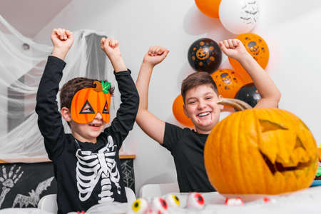 Happy Halloween! Attractive young boy with his big brother are preparing for Halloween party. Brothers in costumes are having fun and scaring each otherの写真素材