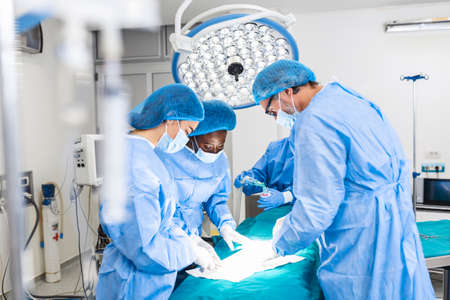Concentrated Surgical team operating a patient in an operation theater. Well-trained anesthesiologist with years of training with complex machines follows the patient throughout the surgery.の写真素材