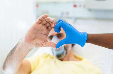 Doctor and patient make finger heart shape wearing blue disposable latex glove, rubber glove for professional medical safety and hygiene protection from Coronavirus disease COVID-19 and surgeryの写真素材