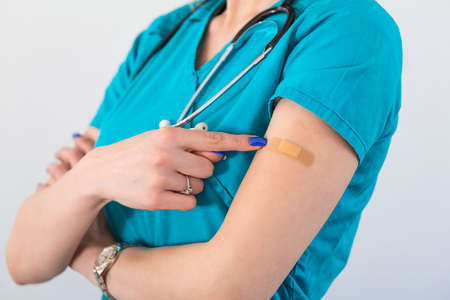 Young woman octor with adhesive bandage on her arm after Coronavirus vaccine. First aid. Medical, pharmacy and healthcare concept.の写真素材