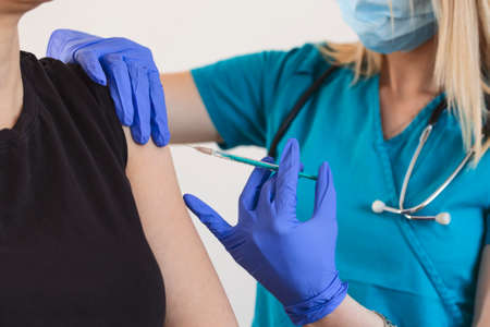 Female doctor or nurse giving shot or vaccine to a patient's shoulder. Vaccination and prevention...