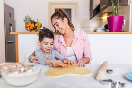 Happy loving family are preparing bakery together. Mother and child son boy are cooking cookies and having fun in the kitchen. Homemade food and little helper.の写真素材
