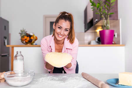kitchen prepares flour doughHappy attractive young adult woman lady housewife baker holding pin rolling dough on kitchen table baking pastry concept cooking cake biscuit doing bakery at homeの写真素材