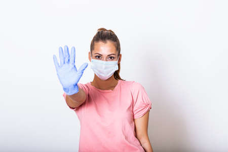 Portrait of young woman wearing face protective mask to prevent Coronavirus and anti-smog. Portrait of young woman wearing face mask showing stop sign with her hand. Covid-19 prevention conceptの写真素材