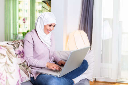 Attractive female Arabic working on laptop computer and paperwork's on desk. Muslim Businesswoman...