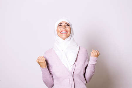 Beautiful muslim woman wearing hijab celebrating for good news. Beautiful young Muslim woman wearing a hijab on her headの写真素材
