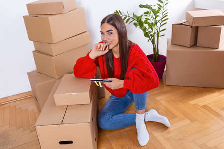 A young beautiful women makes her notes and plans in her new flat,apartment. Young woman packing...