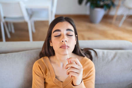 Young woman holding self testing self-administrated swab and medical tubeの写真素材