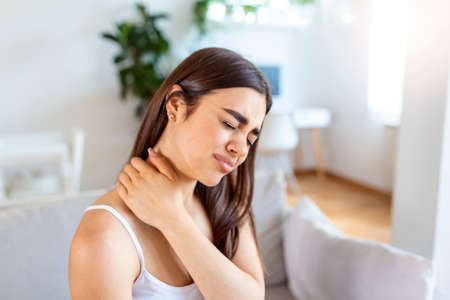 Tired woman massaging stiff sore neck, tensed muscles fatigued from computer work in incorrect posture while feeling hurt joint shoulder back pain ache. Fibromyalgia conceptの写真素材