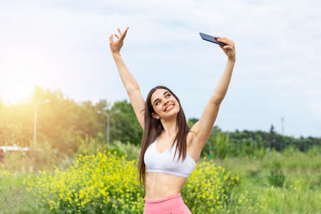 Fitness selfie woman self portrait after workout. Sport athlete taking selfies photo after working out running and training outdoors. Fit female Caucasian sport model smiling happy.の写真素材