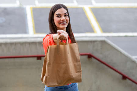 Express grocery delivery service. Smiling young woman looking at camera holding eco bag deliver...