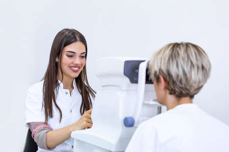 Female doctor ophthalmologist is checking the eye vision of attractive young woman in modern clinic. Doctor and patient in ophthalmology clinic.の写真素材