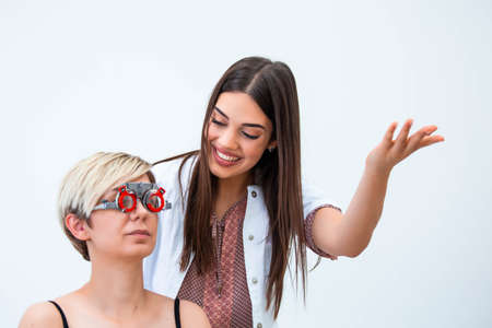 Ophthalmologist examining woman with optometrist trial frame. female patient to check vision in ophthalmological clinic.の写真素材