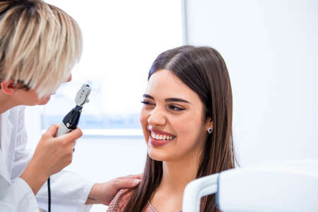 Eye health cheking with ophthalmological equipment in the laboratory. Using special device oculist trying to improve vision of young pretty girl. Working with medical devices for eye healthの写真素材