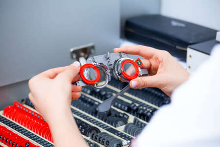 Talented skillful optician choosing lenses for trial spectacles.