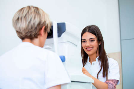 Female doctor ophthalmologist is checking the eye vision of attractive young woman in modern clinic. Doctor and patient in ophthalmology clinicの写真素材