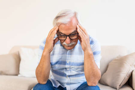 Attack of the monster migraine. Unhappy Retired Senior man holding his head with pain expression ....