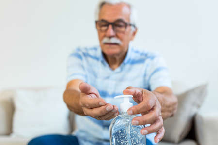 Senior disinfects hands with antibacterial gel. Hand sanitizer alcohol gel rub clean hands hygiene prevention of coronavirus virus outbreak. Old Man using bottle of antibacterial sanitiser soap.の写真素材