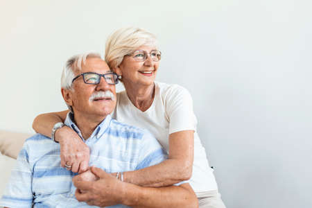 Portrait loving older wife hugging husband sitting on cozy couch. Happy senior mature couple...
