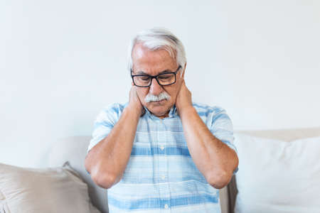 Senior man feeling exhausted and suffering from neck pain, Health concept. Sad senior man with neckache. Elderly man with chronic pain syndrome fibromyalgia suffering from acute neckaches.の写真素材