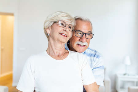 Senior couple standing in the living room. Old couple feeling happy,looking in the distance....