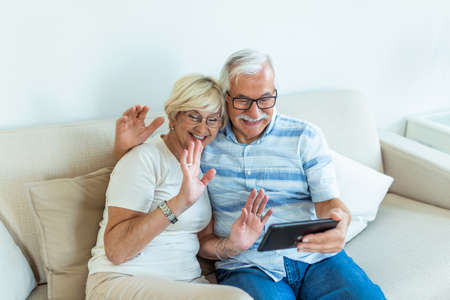 Cheerful senior people websurfing on internet with tablet,family, technology, age and people concept - happy senior couple with tablet pc computer at homeの写真素材