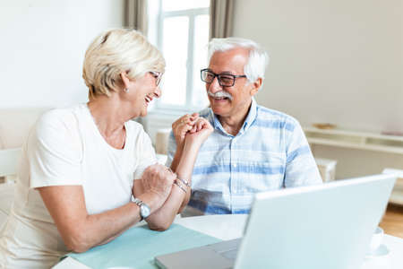 Senior couple is talking online via video connection on the laptop. Having nice time withfriends and family via video call.Holding their hands togetherの写真素材