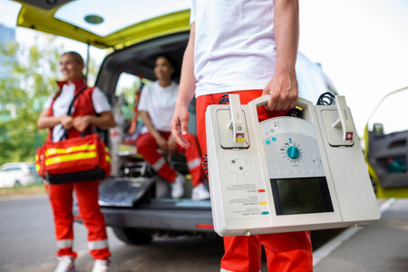 Hand of the doctor with defibrillator. Teams of the Emergency medical service are responding to an...