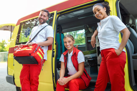 Paramedics and doctor standing on the side ambulance. Doctor is carrying a medical trauma bag. Group...