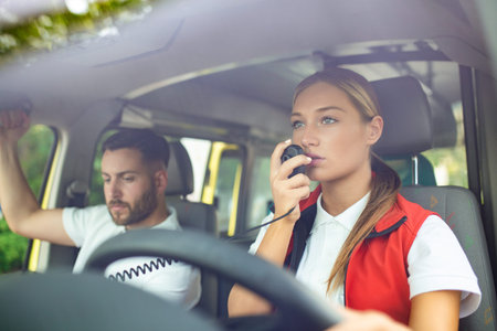 Two paramedics int ambulance. Female paramedic driving ambulance, talking over the radio. Urgent...