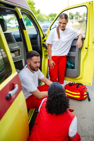 Paramedics and doctor standing on the side ambulance. Doctor is carrying a medical trauma bag. Group...