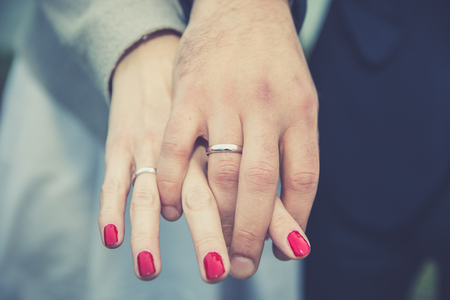 Wedding couple holding hands. Bride and groom's hands with wedding rings, close up.の写真素材