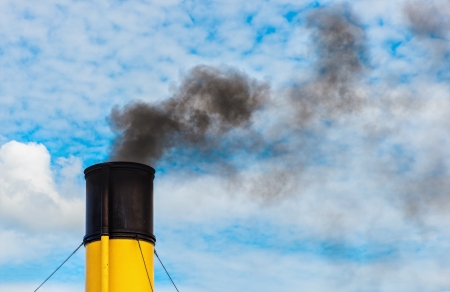 Chimney from steamboat with black coal smoke, yellow and black chimney with cloudy clear skyの写真素材
