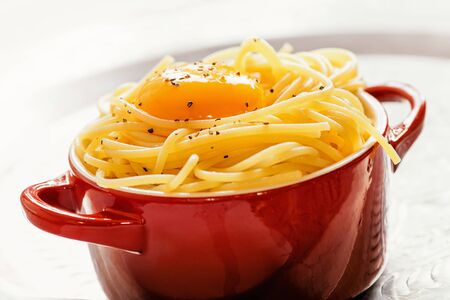 Spaghetti with egg yolke in a small red bowl の写真素材
