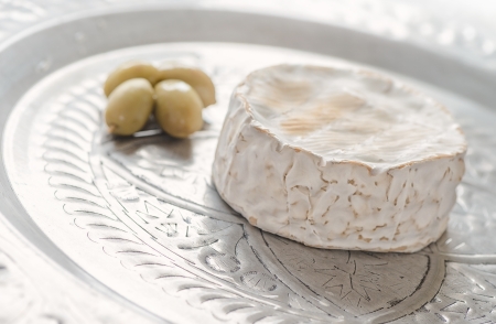 Camembert on a silver tray with green olivesの写真素材