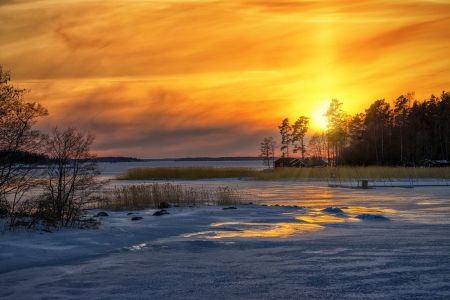 Winter sunset reflections from iced sea with red houses in the distance - Swedenの写真素材