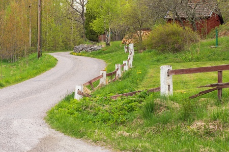 Gravelled countryroad with a red house in Sweden during summerの写真素材