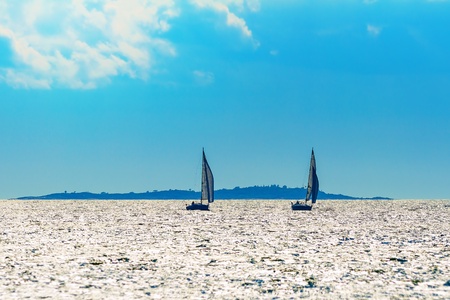 Two sailboat silhouettes in a nice summer day going for port の写真素材