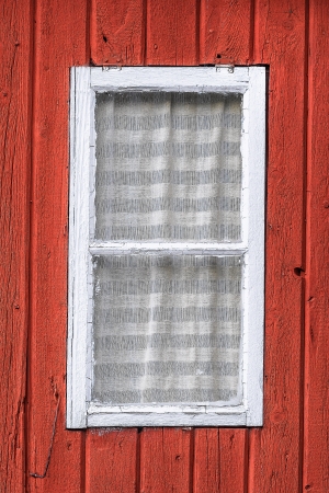 Small white window frame on a red wooden houseの写真素材
