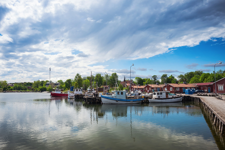 GRISSLEHAMN, NORRTALJE - JUNE 11: Idyllic port in Grisslehamn with fishing vessels and red houses for selling the catch . June 11, 2014 in Grisslehamn, Sweden.のeditorial素材