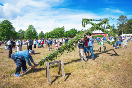 SINGO, NORRTALJE - JUNE 20: Older men raising the traditional maypole in a midsummer celebration with musicans playing. June 20, 2014 in Singo, Sweden.のeditorial素材