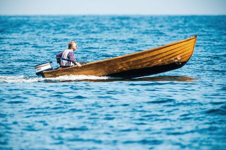 GRISSLEHAMN, NORRTALJE - JULY 11: Man with a fast vintage wooden speedboat at coast of Sweden. July 11, 2014 in Grisslehamn, Sweden.のeditorial素材