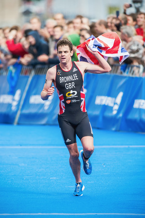 STOCKHOLM - AUG, 23: Winner Jonathan Brownlee grabbing a flag before the finish in the Mens ITU World Triathlon Series event August 23, 2014 in Stockholm, Sweden. Jonathan Brownlee won the race.のeditorial素材