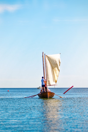 GRISSLEHAMN, Sweden - JUNE, 15: Crew of postal roving boat taking down the sail before the harbour in Grisslehamn, June 15, 2014, in Grisslehamn, Swedenのeditorial素材