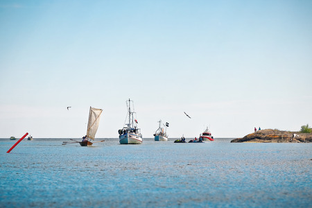 GRISSLEHAMN, Sweden - JUNE, 15: Postal rowing boat with fishing boats and security boats approaching the Grisslehamn harbour, June 15, 2014, in Grisslehamn, Swedenのeditorial素材