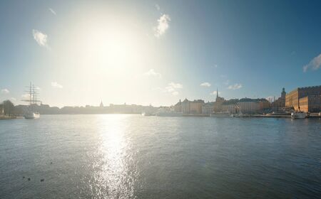 Bright sun over Stockholm cityscape with the old town with old boats and housesの写真素材