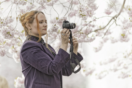 STOCKHOLM, SWEDEN - APRIL 22: Woman taking phone picture (selfie) with backdrop of Cherry trees, April 22, 2015 in Stockholm, Sweden.のeditorial素材