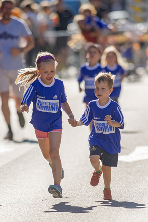 STOCKHOLM, SWEDEN - AUGUST 15, 2015: Sister holding her litttle brothers hand during the Minimil for the youngest runners at Midnattsloppet. The track is 300 meters and the runners are aged 2-8 years.のeditorial素材