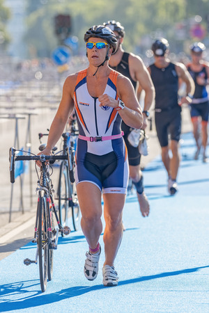 STOCKHOLM - AUG 23, 2015: Male triathletes running with bike and shoes in the transition area the ITU World Triathlon event in Stockholm.のeditorial素材